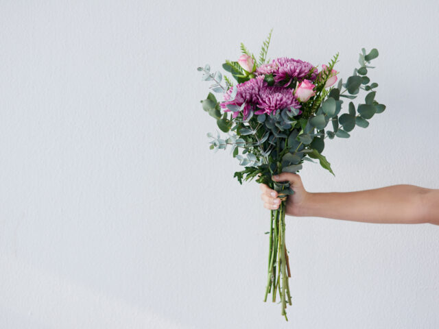 Arm extending out from the side of the frame holding a bunch of flowers AudioXi Campaign